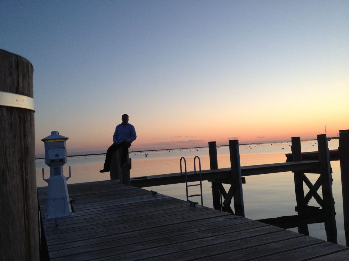 A figure on a dock at sunset